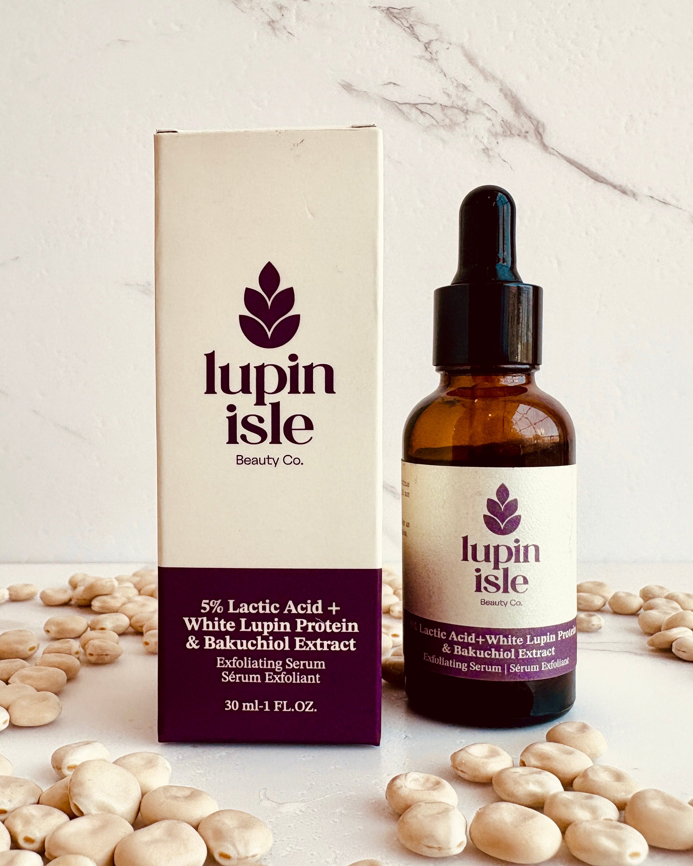 A bottle of Lupin Isle Beauty Co. serum next to its product box, styled with scattered lupin beans on a white marble surface and background.